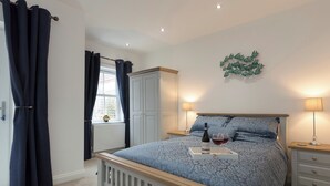 Une chambre à coucher comprenant un lit, deux tables de chevet, une armoire, une fenêtre avec des rideaux et un élément de décoration murale.