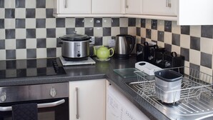 Eine Küche mit kariertem Fliesenspiegel in Schwarz-Weiß, einem Slow Cooker, einem Wasserkocher und einer Kaffeemaschine.