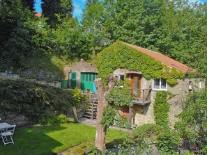 A stone building with a red-tiled roof, green doors, and a small balcony. - Pretty two storey holiday cottage right beside the village stream. (Goathland)