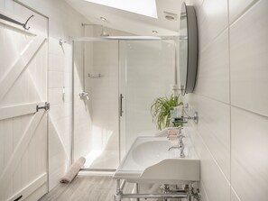 Ein modernes Badezimmer mit Duschkabine aus Glas, einem großzügigen Waschbecken und einem Spiegel.
