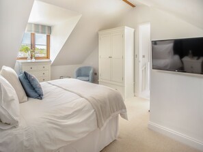 Ein Schlafzimmer mit einem Bett, einem Kleiderschrank, einem Sessel und einem Fernseher.