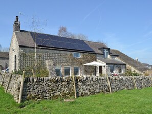A stone house with a solar panel roof, a stone wall, and a small garden. - 4 bedroom accommodation in Wardlow, near Buxton (Wardlow, near Buxton)
