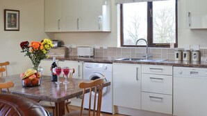 Una cocina moderna con armarios blancos, encimera de granito, lavadora integrada y una ventana con cortina floral.