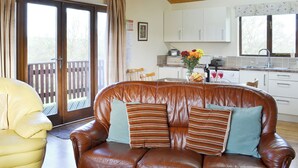 Un salón acogedor con un sofá de cuero marrón, un sillón amarillo y una mesa de comedor de madera.