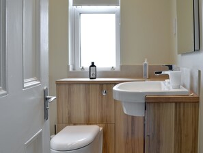 A bathroom with a wooden vanity, a white sink, and a toilet.