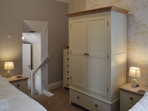 A bedroom with a bed, a wardrobe, two bedside tables with lamps, and a staircase. - 3 bedroom accommodation in Bakewell (Bakewell)