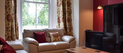 A living room with a sofa, a coffee table, and a TV.