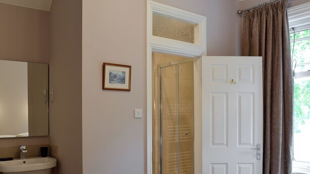 A hotel room with a bathroom, a bed with towels, a framed picture, and a door. - 3 bedroom accommodation in Bakewell (Bakewell)