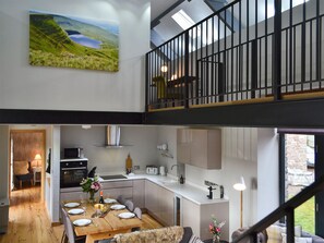 A modern kitchen with a dining area, a staircase, and a large window.