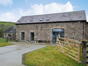 A stone building with a large entrance door, a small window, and a wooden gate.