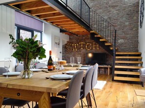 A dining area with a wooden table set for four, a bottle of wine, and a cake on the table.