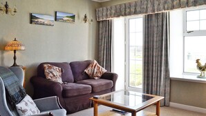 Una sala de estar con sofá, sillón y una mesa de centro de vidrio.