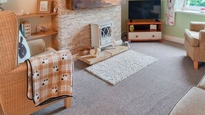 A cozy living room with a stone wall, a fireplace, a television, and a window with curtains. - 2 bedroom accommodation in Loftus, near Saltburn-by-the-Sea (Loftus, near Saltburn-by-the-Sea)