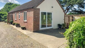 Une maison de plain-pied en briques, avec un toit en tuiles, une grande porte-fenêtre coulissante et un petit porche.