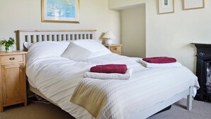 A neatly made bed with white linens, a wooden headboard, and two red towels on the bed. There is a nightstand with a lamp and a small plant beside the bed. - 2 bedroom accommodation in Burtersett, near Hawes (Burtersett, near Hawes)