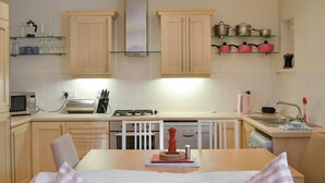 Una cocina con gabinetes de madera, microondas, estufa y pileta.