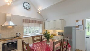 Une cuisine équipée d’une table à manger, de chaises, d’une horloge et d’un réfrigérateur.