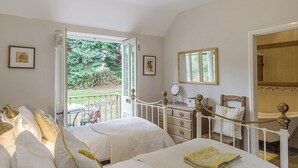 Une chambre avec deux lits, une commode, un miroir et une vue sur le jardin.