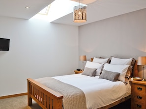 Ein Schlafzimmer mit einem Bett, Nachttischlampen, einem Fernseher und einer Deckenleuchte.