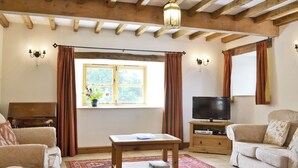 A living room with a sofa, a coffee table, a TV, and a window with curtains. - 3 bedroom accommodation in Pedairffordd (Pedairffordd)