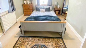 Un dormitorio con cama, cómoda, mesita de noche y un espejo grande.