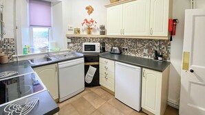 Una cocina con armarios blancos, microondas, tostadora y pileta.