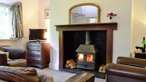 Una sala de estar con chimenea, sofás de cuero, un televisor y un espejo sobre la chimenea.