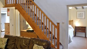 Una escalera con barandillas de madera que lleva a un dormitorio con cama y mesita de noche.