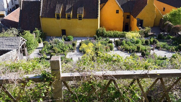 A coastal village with traditional architecture, including yellow and red buildings, and a clear view of the sea.
