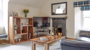 A living room with a fireplace, a television, a wooden coffee table, and a blue sofa.
