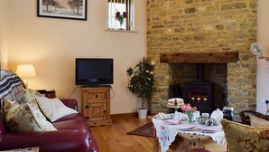 Una sala de estar acogedora con chimenea de piedra, televisión y un espacio de descanso cómodo.