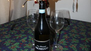 Une bouteille de vin et deux verres sur une table recouverte d’une nappe à motifs de houx.