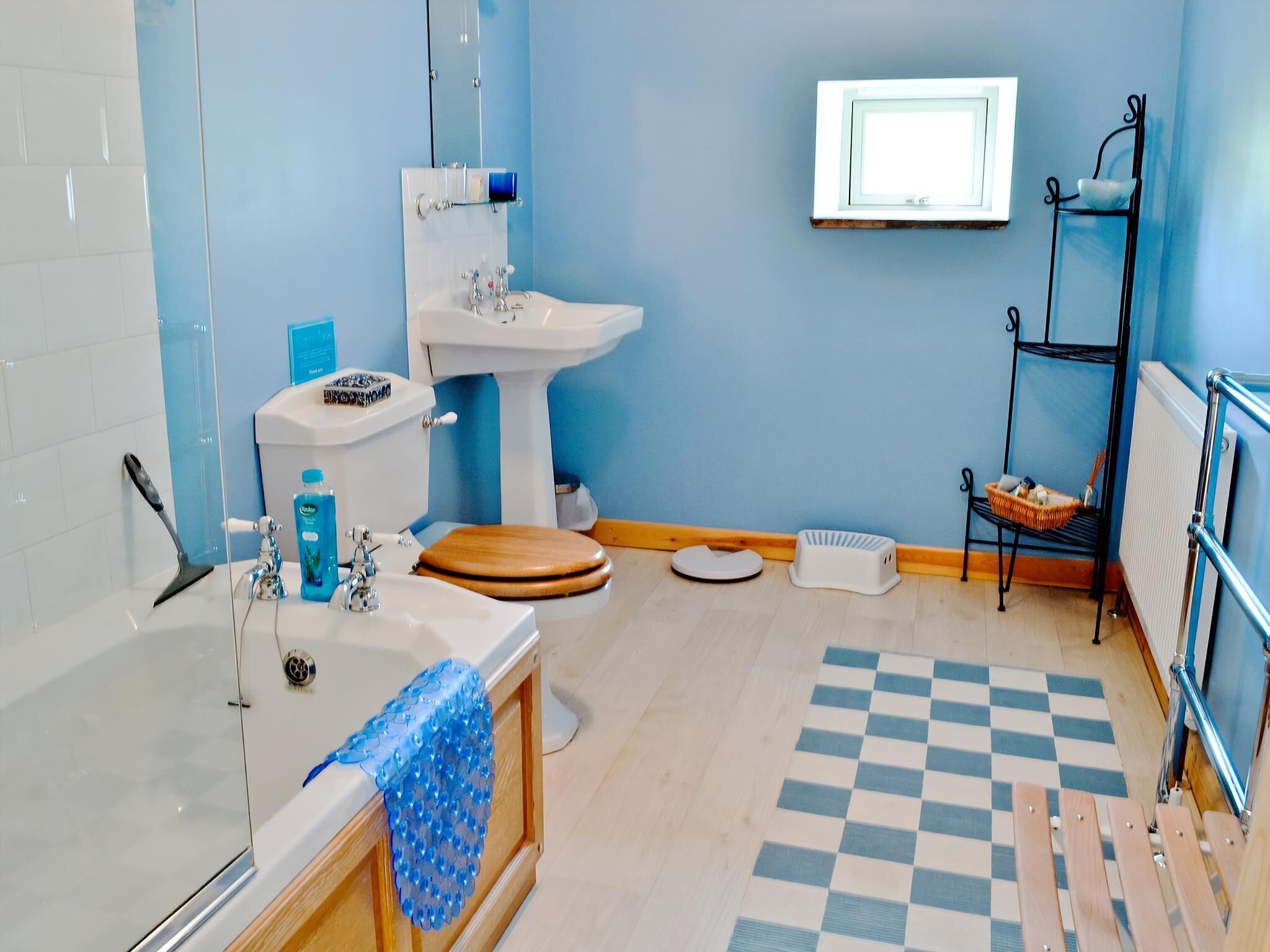 A bathroom with a toilet, sink, bathtub, and a shelf with toiletries.