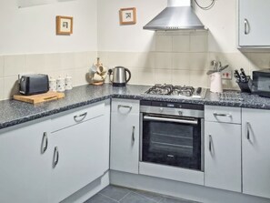 A kitchen with white cabinets, a built-in oven, a stove, and a toaster.