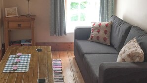 Una sala de estar acogedora con un sofá, una mesa de centro de madera y una mesita auxiliar con una lámpara.