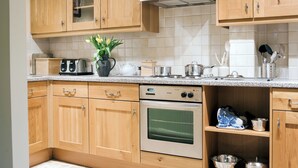 Une cuisine avec des meubles de rangement en bois, une cuisinière et un four à micro-ondes.
