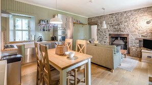 A modern kitchen with a dining area, stone wall, and fireplace. - 2 bedroom accommodation in Bankfoot, near Dunkeld (Bankfoot, near Dunkeld)
