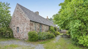 A stone house with a gravel driveway and a wooden bench. - 2 bedroom accommodation in Bankfoot, near Dunkeld (Bankfoot, near Dunkeld)