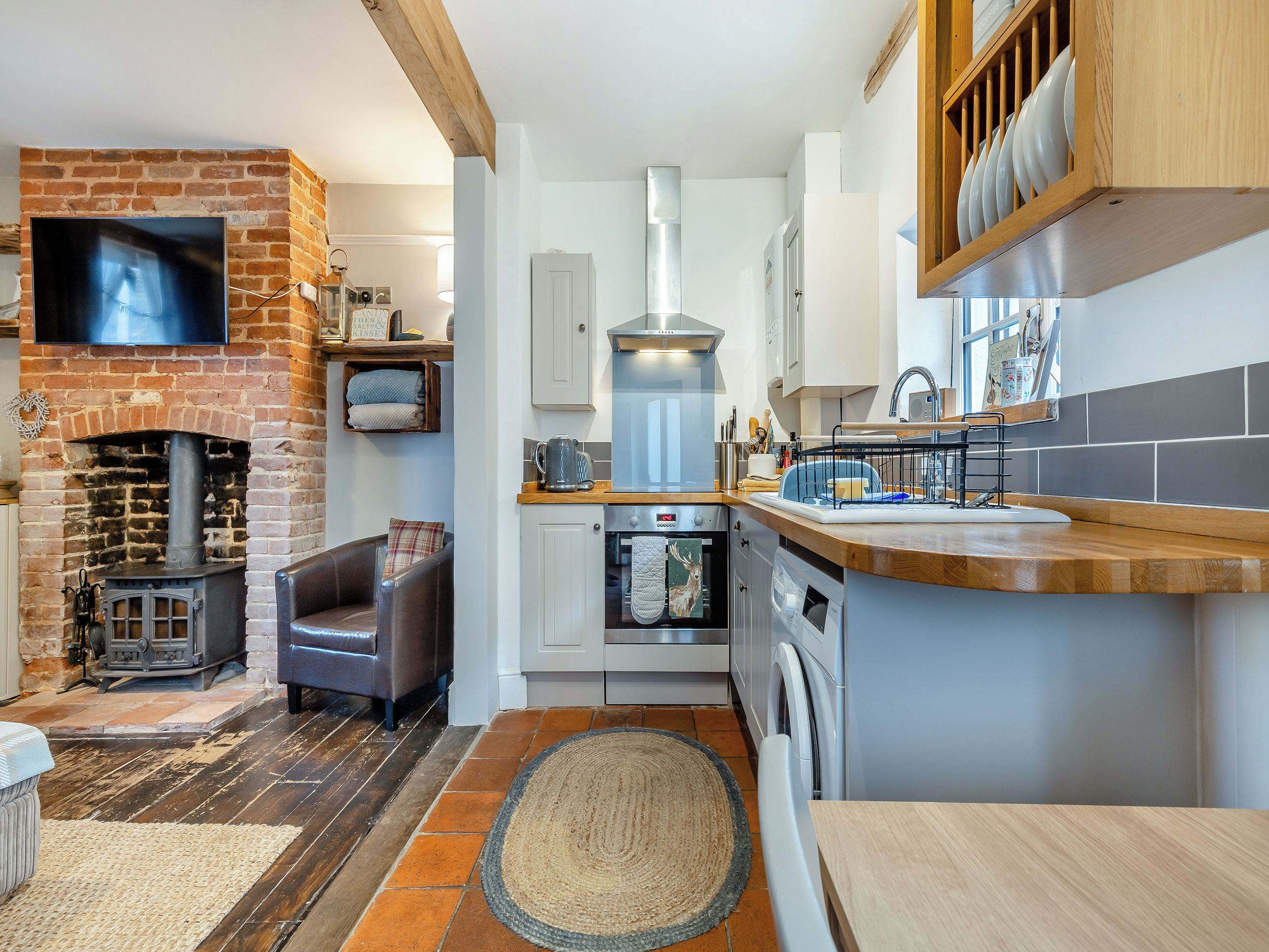 A modern kitchen with a built-in oven, a washing machine, and a fireplace. - 3 bedroom accommodation in Cromer (Cromer)