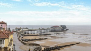 A coastal promenade with a pier extending into the sea, a sandy beach, and buildings along the promenade. - 3 bedroom accommodation in Cromer (Cromer)