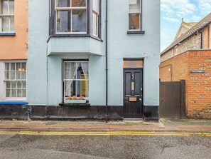 A two-story building with a black door and a window with a curtain. - 3 bedroom accommodation in Cromer (Cromer)