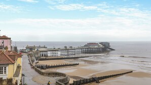 A coastal promenade with a pier extending into the sea, a sandy beach, and buildings along the promenade. - 3 bedroom accommodation in Cromer (Cromer)
