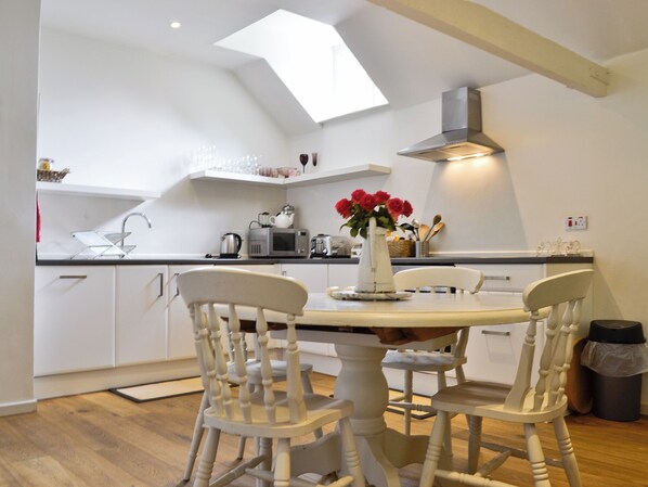 A kitchen with white cabinets, a round dining table, and two chairs.