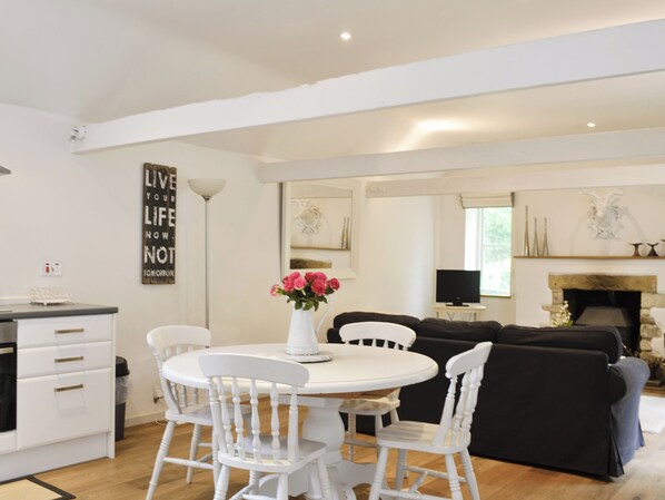A modern living room with a fireplace, white furniture, and a decorative wall sign.