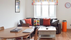 A modern living room with a leather sofa, a wooden coffee table, and a dining table. - 2 bedroom accommodation in Bowness-on-Windermere (Bowness-on-Windermere)