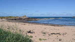 A beach with rocky outcrops and calm waters.