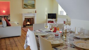 A dining area with a fireplace, a television, and a painting on the wall.