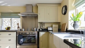 A kitchen with a Kenwood oven, a stove, a bread box, and a clock on the wall. - Hungate Garden Cottage (Pickering)