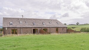 Ein zweistöckiges Steinhaus mit geneigtem Dach, zahlreichen Fenstern und einer Holztür.