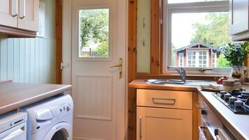 A compact kitchen with a washing machine, a sink, and a stove.